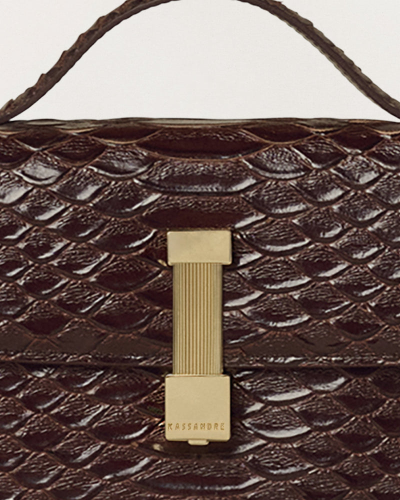 Kassandre Colonne clutch in brown python-effect leather with gold hardware, three quarter view