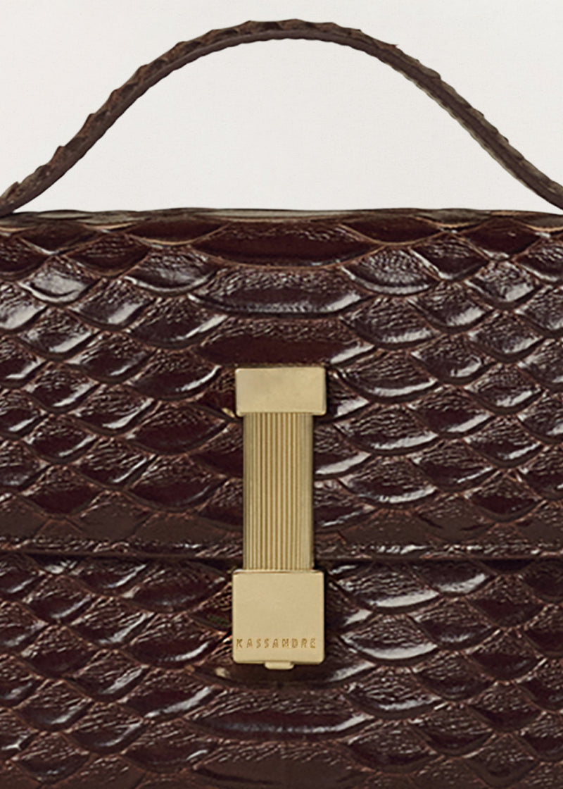 Kassandre Colonne clutch in brown python-effect leather with gold hardware, three quarter view
