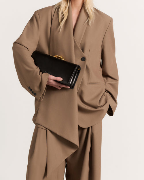 Kassandre Deva clutch in black cow leather with gold hardware, Art Deco geometry,removable strap , crossbody bag , worn view