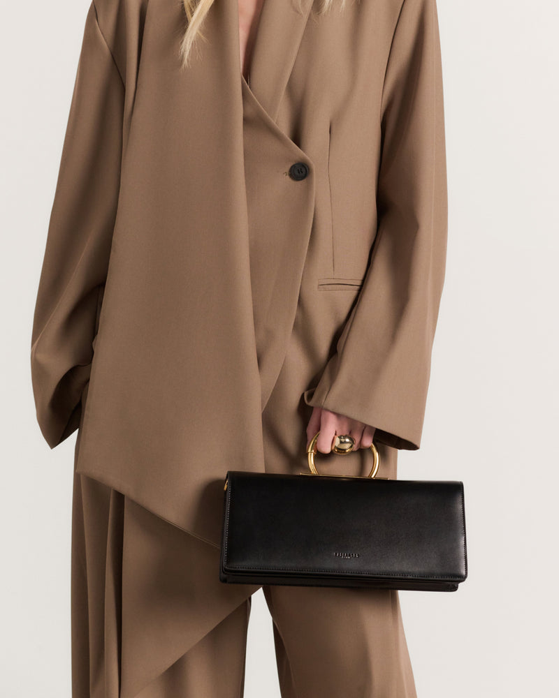 Kassandre Deva clutch in black cow leather with gold hardware, Art Deco geometry,removable strap , crossbody bag , worn view
