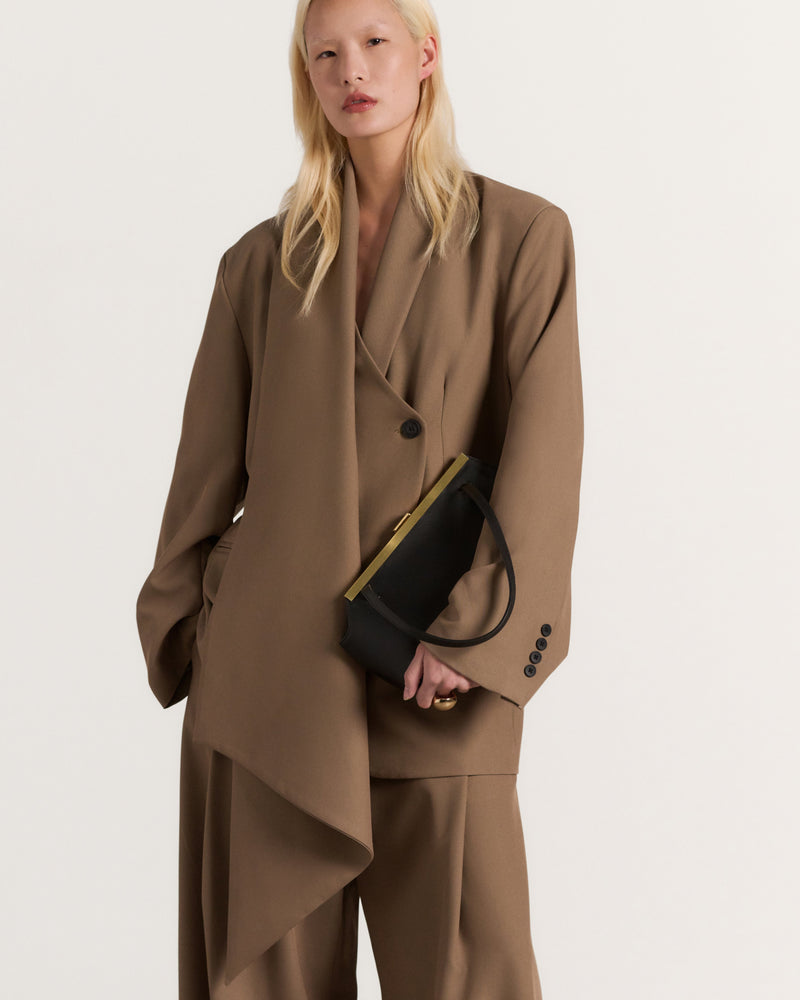 Kassandre Eileen asymmetric shoulder bag in black cow leather, architectural line, gold frame,worn front view