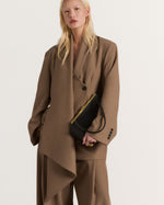Kassandre Eileen asymmetric shoulder bag in black cow leather, architectural line, gold frame,worn front view