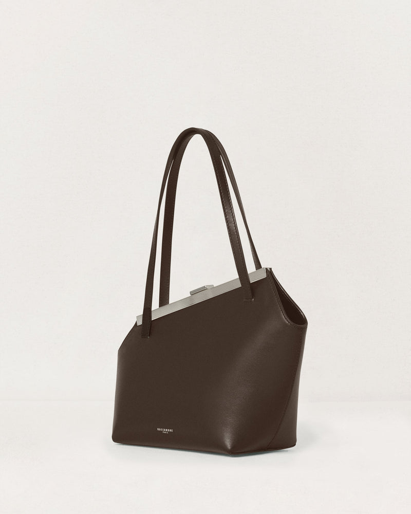 Kassandre Eileen asymmetric shoulder bag in brown cow leather, silver frame, graphic geometry, three quarter view 