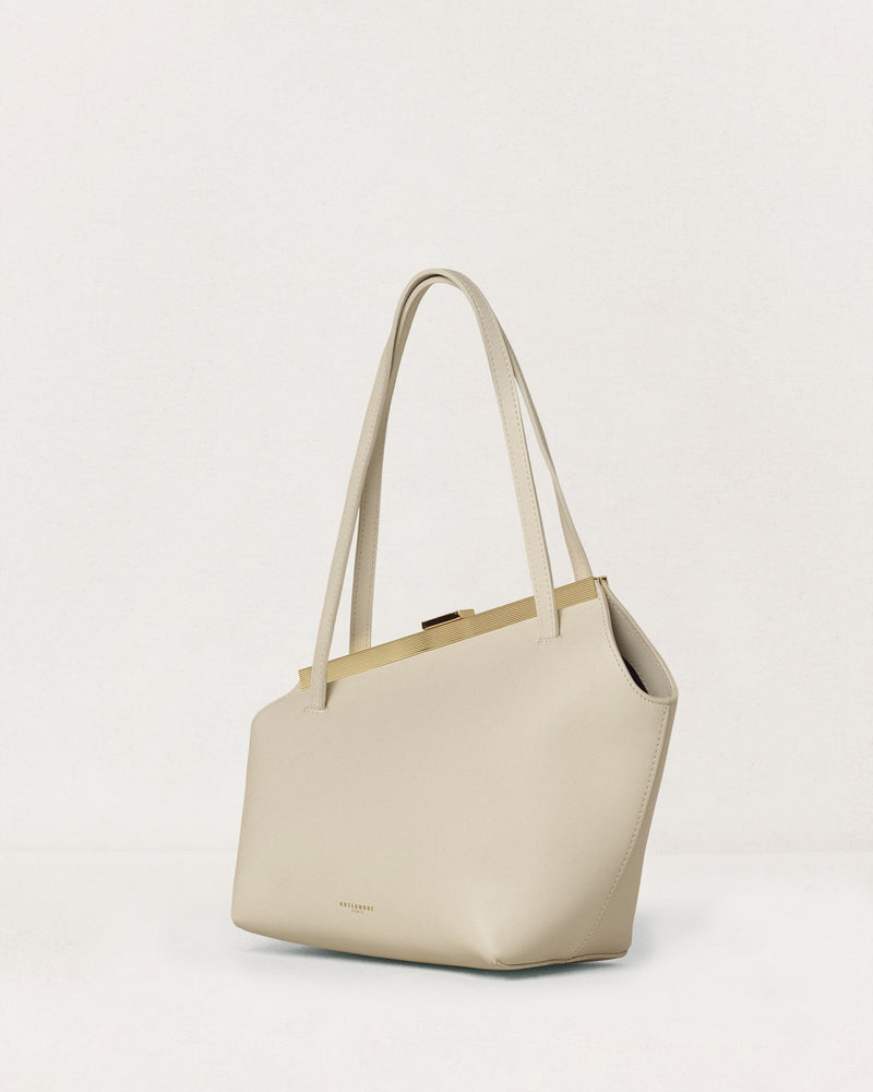 Kassandre Eileen asymmetric shoulder bag in off-white cow leather, clean line, gold frame, three quarter view