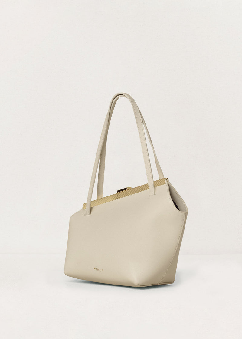 Kassandre Eileen asymmetric shoulder bag in off-white cow leather, clean line, gold frame, three quarter view