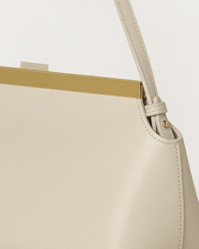 Kassandre Eileen shoulder bag in off-white cow leather with gold striped metal frame, detail handle view