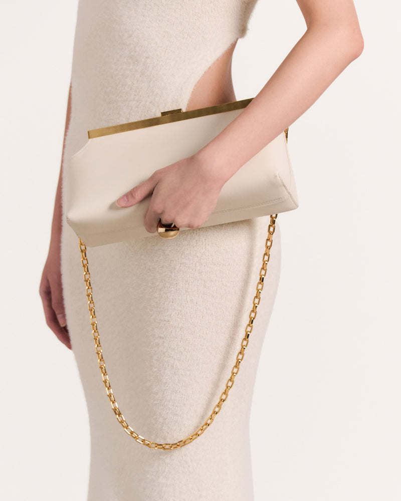 Kassandre Eileen shoulder bag in off-white cow leather with gold striped metal frame, worn view