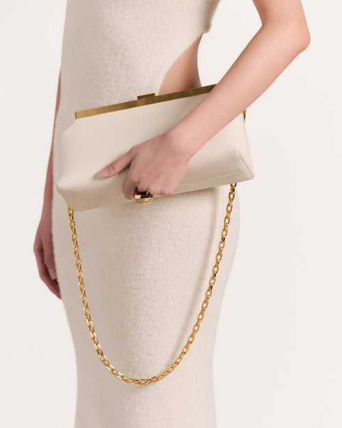 Kassandre Eileen shoulder bag in off-white cow leather with gold striped metal frame, worn view